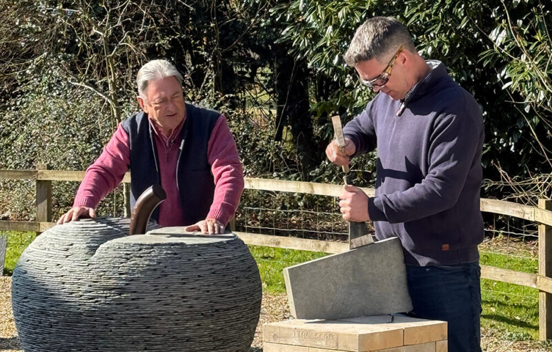 James Parker sculptor demonstrating the process of riving slate while appearing on Love Your Weekend, working on a slate apple sculpture.