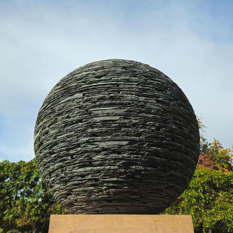 Bespoke stacked slate sphere sculpture by James Parker on a Corsehill sandstone base, created to complement a private architectural setting.