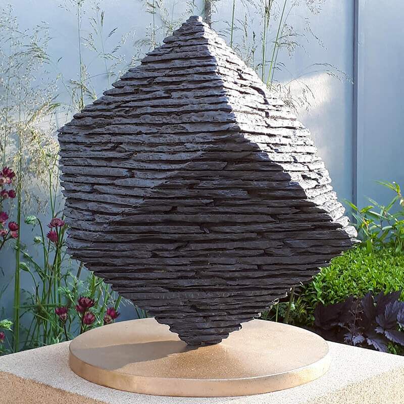 Limited edition bronze cube sculpture by James Parker balanced on its corner at RHS Chelsea Flower Show