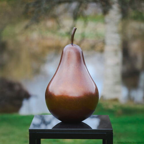 Limited edition bronze pear sculpture with a rich russet brown patina by James Parker displayed on a plinth