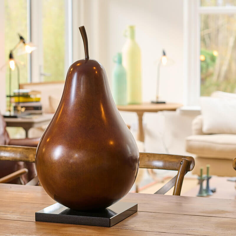 Limited edition bronze pear sculpture by James Parker displayed on a plinth within a refined kitchen interior