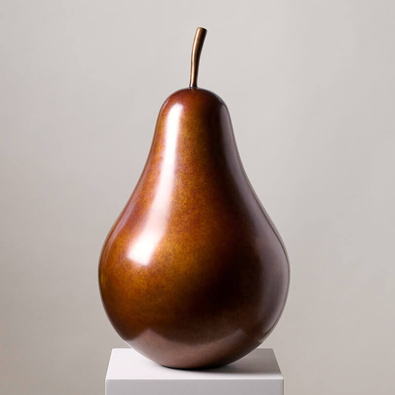 Limited edition bronze pear sculpture by James Parker displayed on a white plinth in a minimalist gallery setting