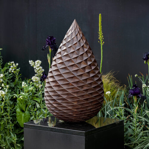 80cm limited edition bronze pine cone sculpture by James Parker on a black granite plinth in a garden