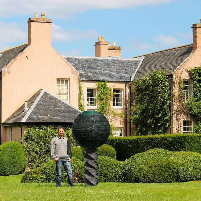 Monumental glass and slate sculpture “Light” by James Parker installed at Auchindoune House, featuring a stacked glass sphere atop a slate helix.
