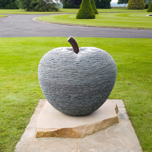 Stone apple sculpture with bronze stalk by James Parker installed on a private estate.