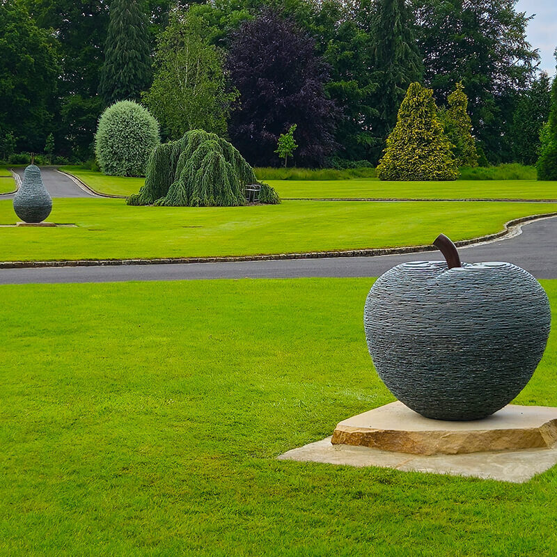 Stone apple and pear sculptures by James Parker positioned at the entrance to a country estate.
