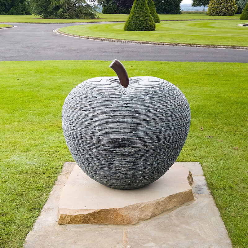Stone apple sculpture with bronze stalk by James Parker installed on a private estate.