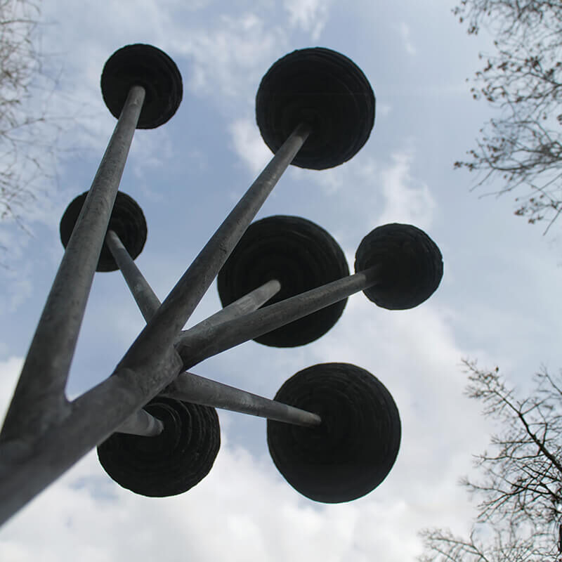 Cloud Tree slate sculpture by James Parker, featuring suspended stone spheres mounted on a steel structure against the sky.
