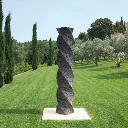Twisted stacked slate column sculpture by James Parker installed outdoors, showing layered stone and vertical form.