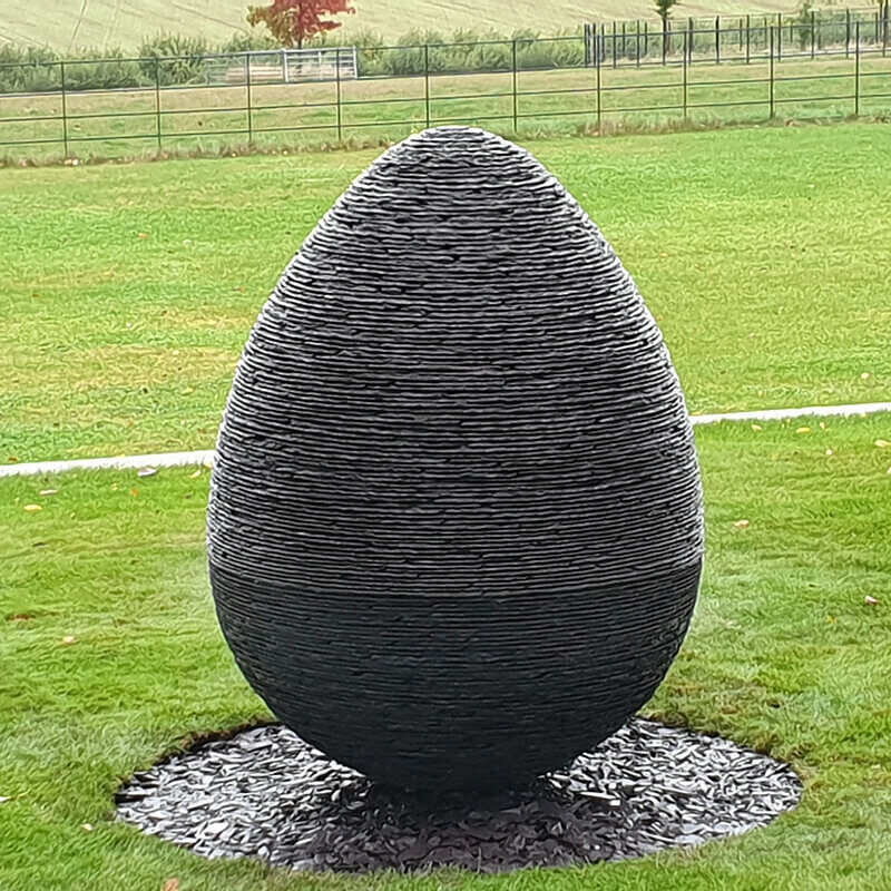 Stacked slate egg sculpture in Penrhyn Welsh slate by James Parker, installed within a private estate landscape.