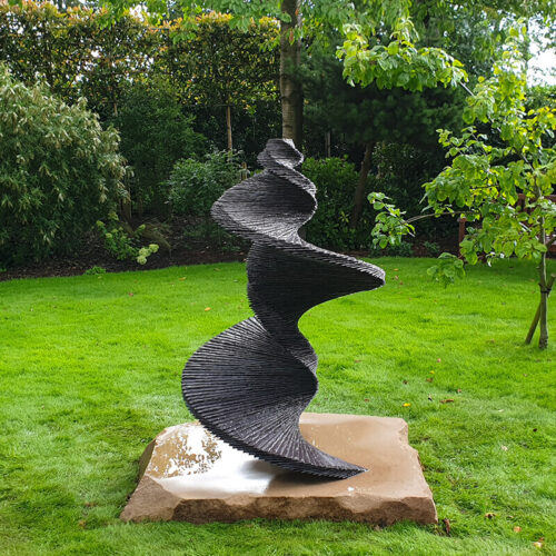 Stacked slate spiral sculpture “DNA of a Dancer” by James Parker, inspired by the double helix and designed as a garden focal point.