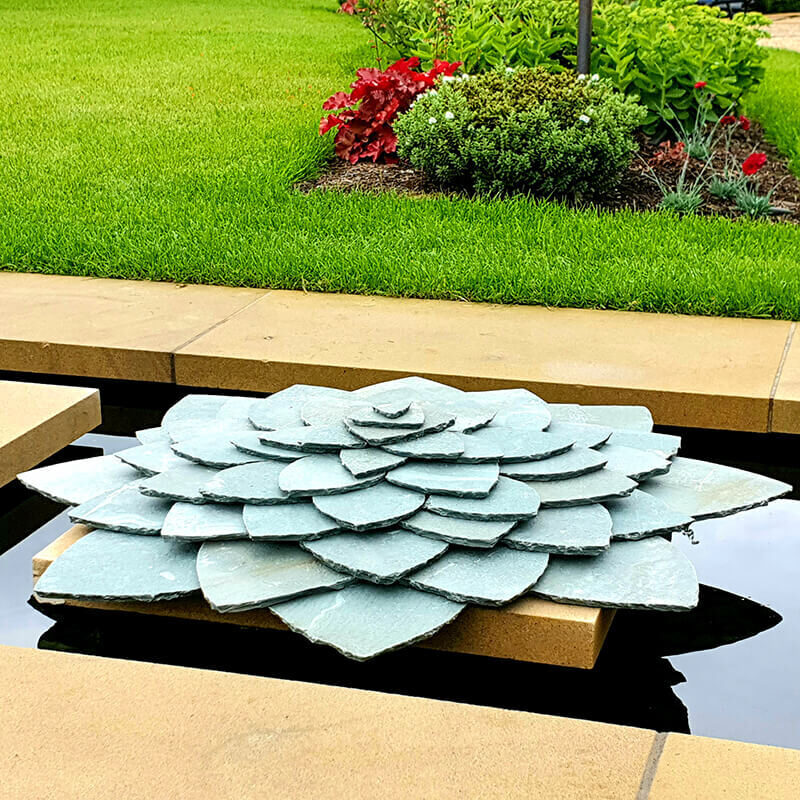 Geometry of Plants green slate sculpture by James Parker, inspired by lotus form and positioned within a garden water rill.
