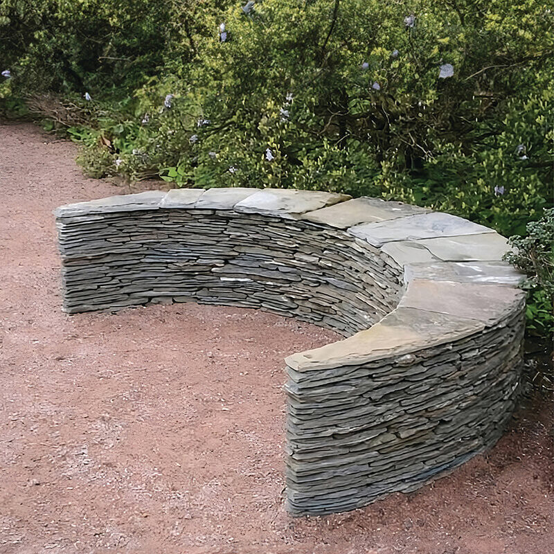 Crescent-shaped slate Moon Seat by James Parker, installed as sculptural seating within a walled garden setting.