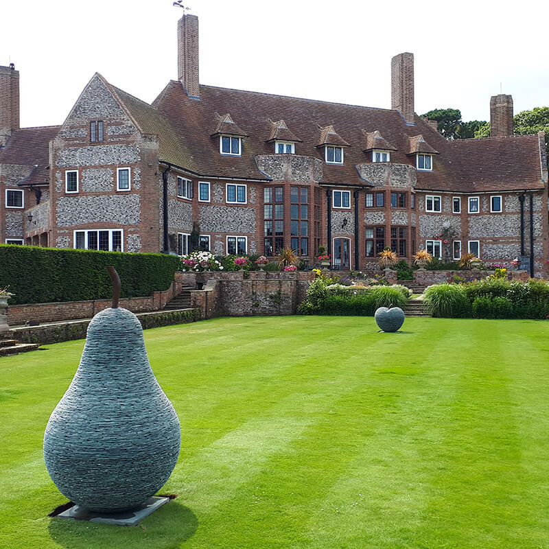 Contemporary stacked slate pear sculpture by James Parker positioned on a formal country house lawn.