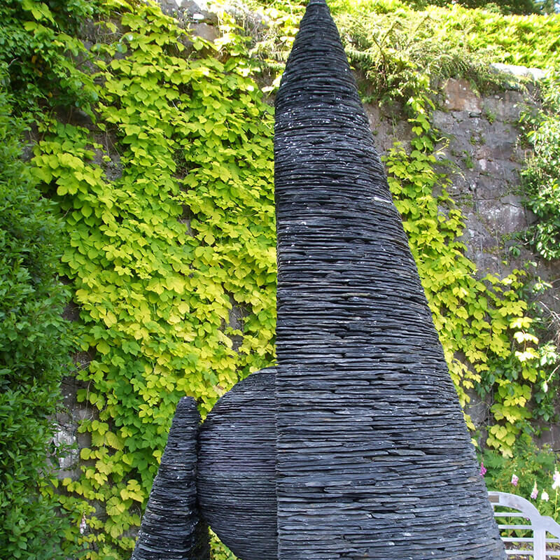 Sheltered Existence monumental slate landscape sculpture by James Parker at Inverewe Gardens, featuring a split conical form enclosing a sphere.