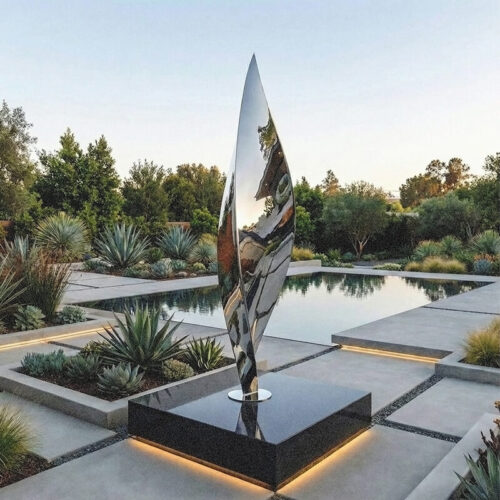 Monumental mirror-polished stainless steel Leaf sculpture installed as an obelisk-like focal point in a contemporary landscaped garden.