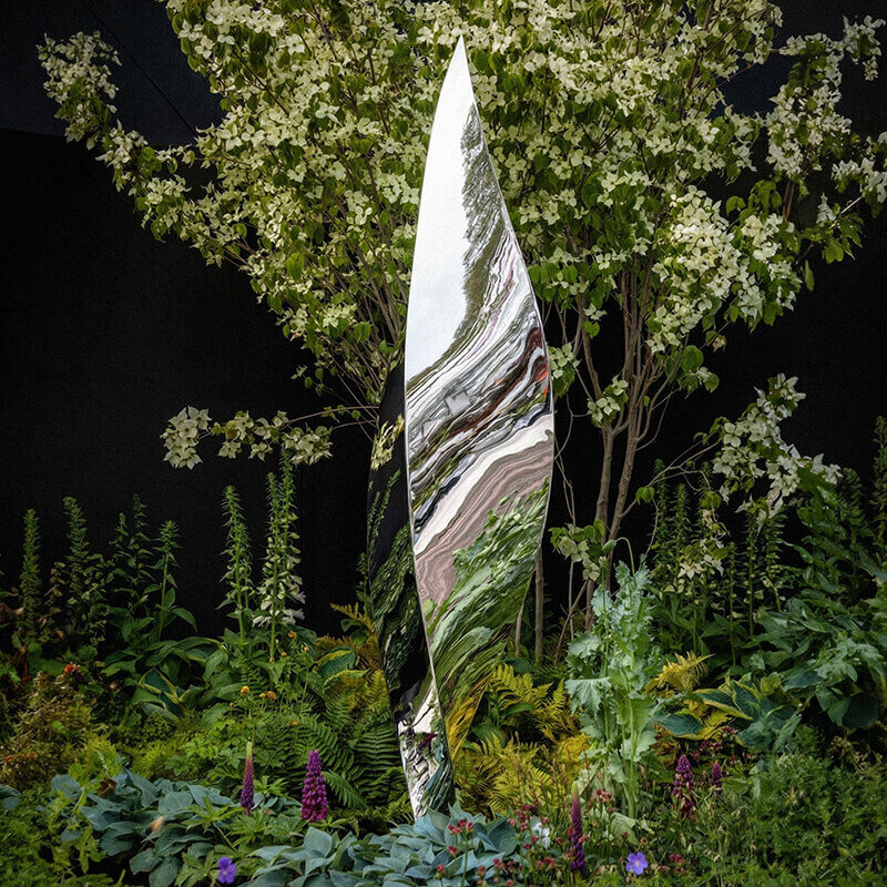 Mirror-polished stainless steel Leaf sculpture by James Parker displayed at the RHS Chelsea Flower Show surrounded by planting.