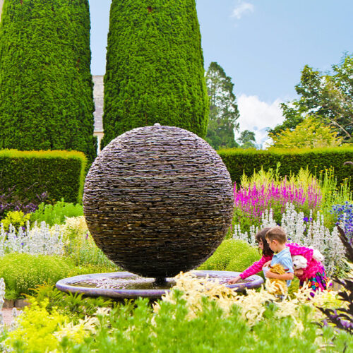 The Sun, a slate sphere water sculpture by James Parker, installed in the walled garden at Cawdor Castle with water flowing over reclaimed stone.