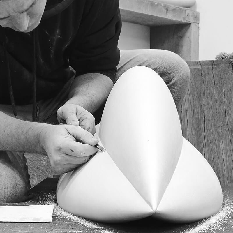 James Parker using a hand tool to refine the plaster pattern for the sculpture “Bud” in his workshop.