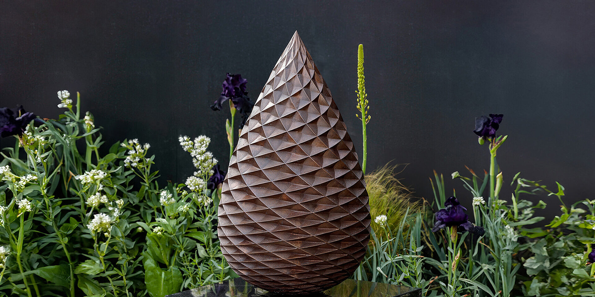 Large-scale limited edition bronze pine cone sculpture by James Parker installed in a private garden in the south of England.