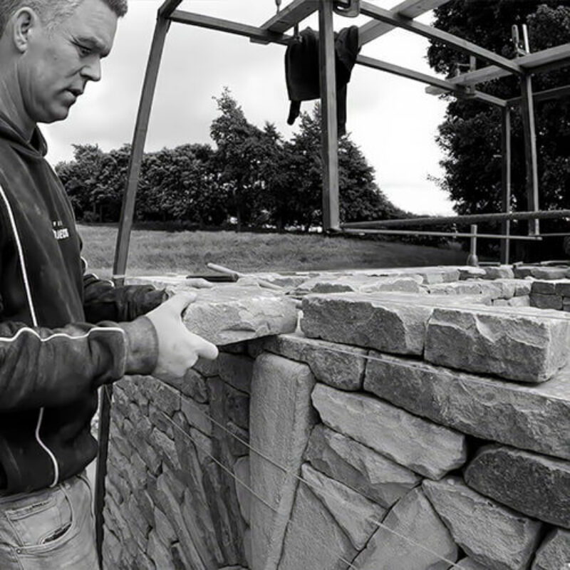 James Parker placing a stone above the keystone while building the dry stone doocot using traditional walling techniques.